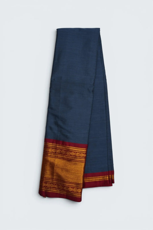 Bhavana Handlooms steel blue mercerized cotton saree with rich zari border and red trim. Lightweight and soft finish.